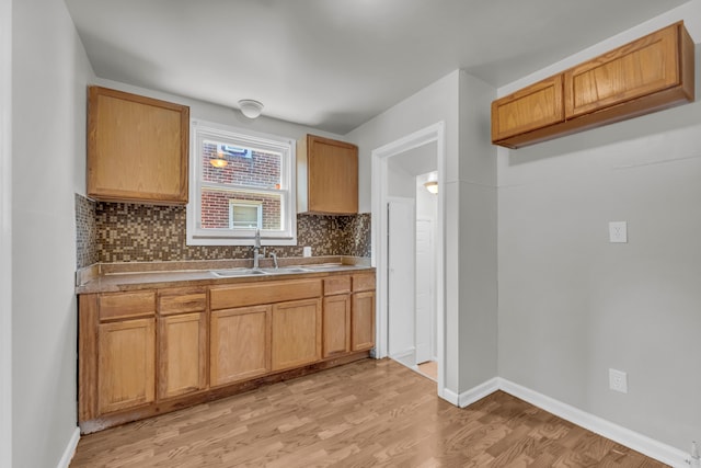 kitchen featuring light wood-type flooring, sink, and tasteful backsplash