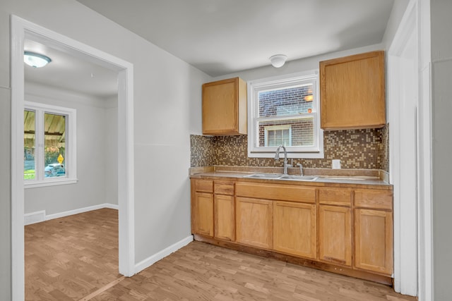 kitchen featuring decorative backsplash, light wood-type flooring, and sink