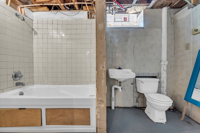 bathroom with a bathing tub, toilet, concrete flooring, and sink