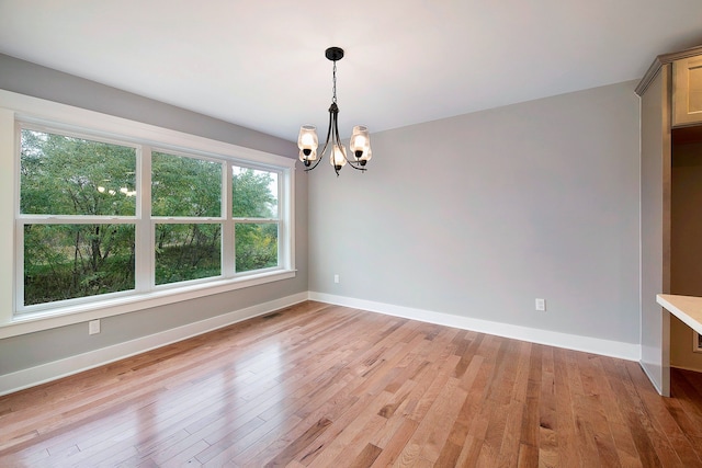 unfurnished dining area featuring light hardwood / wood-style floors and an inviting chandelier