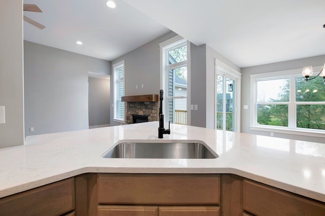 kitchen featuring a fireplace, plenty of natural light, a notable chandelier, and sink