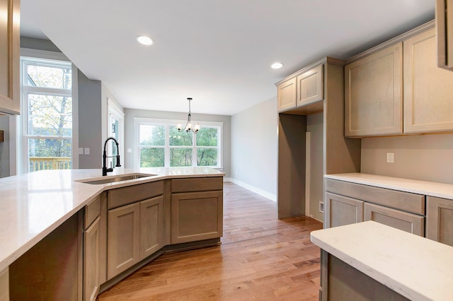 kitchen with a chandelier, light hardwood / wood-style floors, hanging light fixtures, and sink