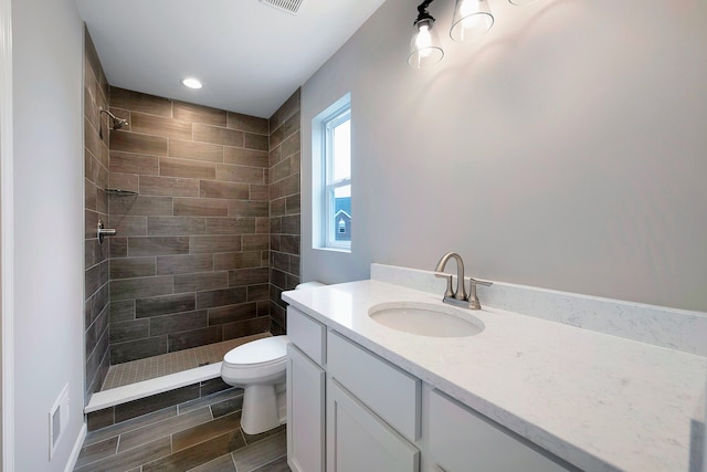 bathroom featuring vanity, toilet, and tiled shower