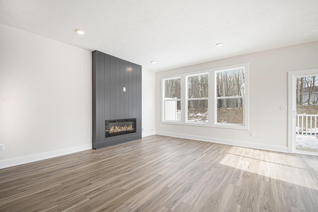 unfurnished living room with hardwood / wood-style flooring, a large fireplace, and a textured ceiling