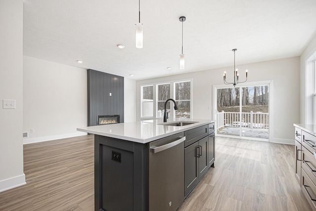 kitchen with a kitchen island with sink, sink, decorative light fixtures, and stainless steel dishwasher