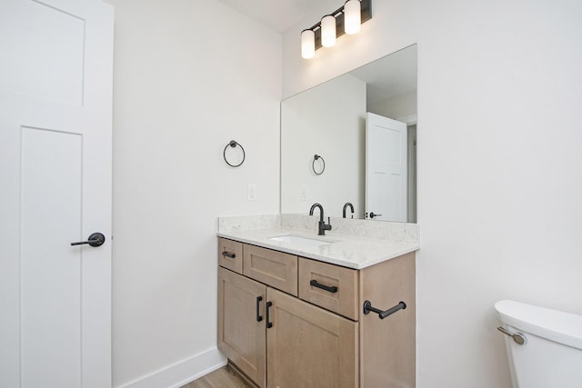 bathroom with vanity, toilet, and hardwood / wood-style floors