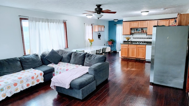 living room featuring a textured ceiling, ceiling fan, dark wood-type flooring, and sink
