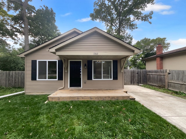 bungalow with a wooden deck and a front lawn