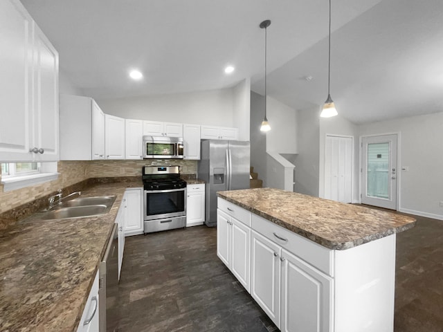 kitchen with a center island, white cabinets, vaulted ceiling, and appliances with stainless steel finishes