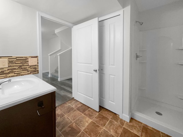 bathroom with backsplash, vanity, and walk in shower