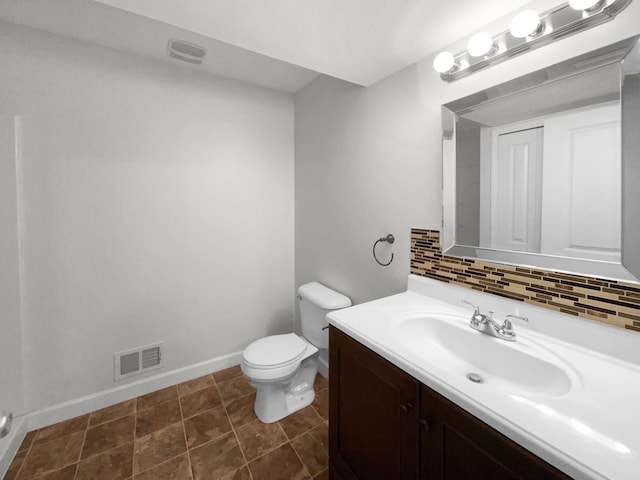 bathroom with tile patterned flooring, vanity, toilet, and tasteful backsplash