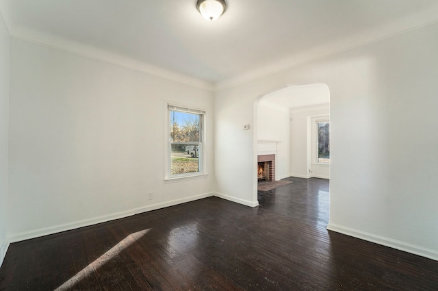 unfurnished living room with dark hardwood / wood-style floors, a brick fireplace, and crown molding