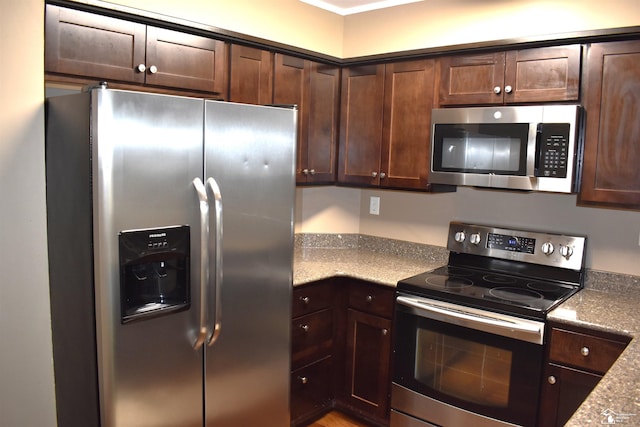 kitchen featuring dark brown cabinetry, light stone countertops, and stainless steel appliances