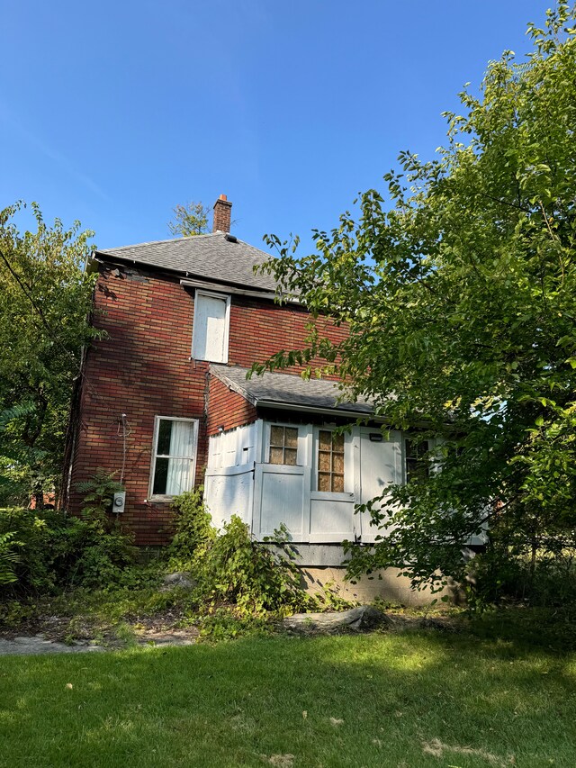 2986 Cadillac Blvd, Detroit, MI 48214 - rear view of property with a chimney, brick siding, and a lawn