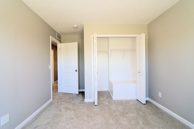 unfurnished bedroom featuring light carpet and a closet