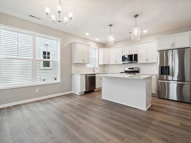 kitchen featuring decorative light fixtures, stainless steel appliances, decorative backsplash, and white cabinets