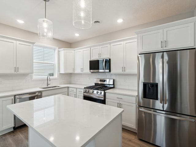 kitchen with white cabinetry, sink, hanging light fixtures, a center island, and stainless steel appliances