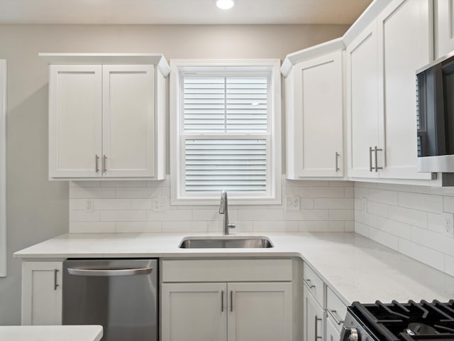 kitchen with white cabinetry, appliances with stainless steel finishes, sink, and backsplash