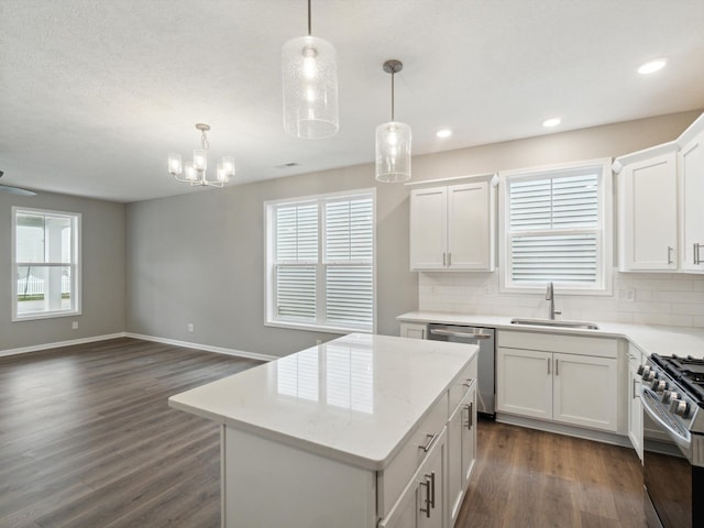 kitchen with pendant lighting, appliances with stainless steel finishes, white cabinetry, tasteful backsplash, and a kitchen island