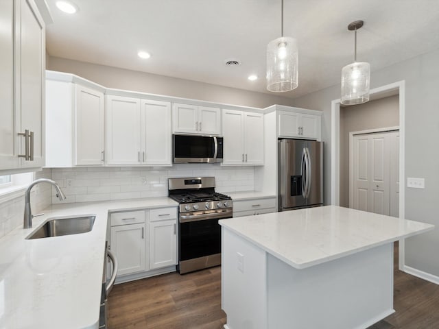 kitchen with pendant lighting, sink, white cabinetry, stainless steel appliances, and light stone countertops