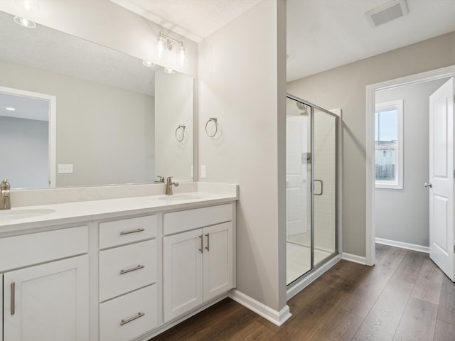 bathroom with hardwood / wood-style flooring, vanity, and an enclosed shower