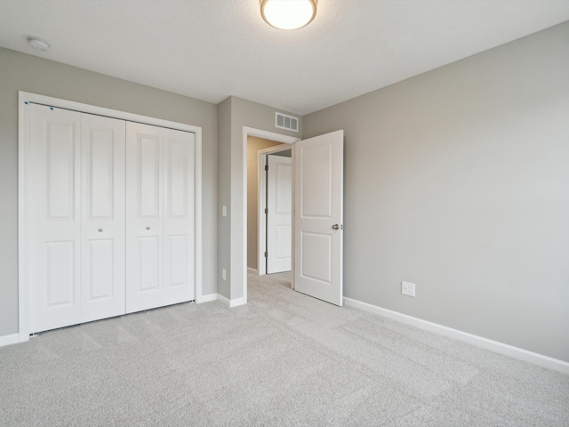 unfurnished bedroom with light carpet, a closet, and a textured ceiling