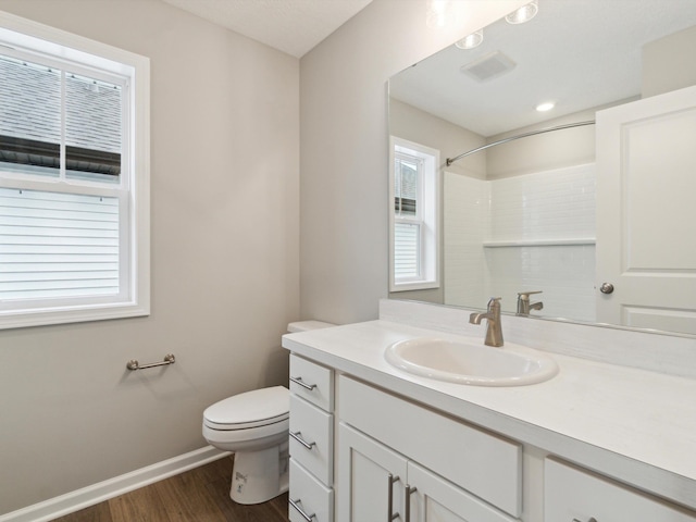 bathroom featuring vanity, hardwood / wood-style floors, walk in shower, and toilet