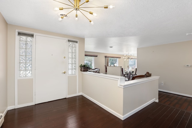 entrance foyer featuring a textured ceiling, a baseboard heating unit, dark wood-type flooring, and a chandelier