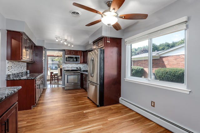 kitchen featuring baseboard heating, a healthy amount of sunlight, tasteful backsplash, and stainless steel appliances