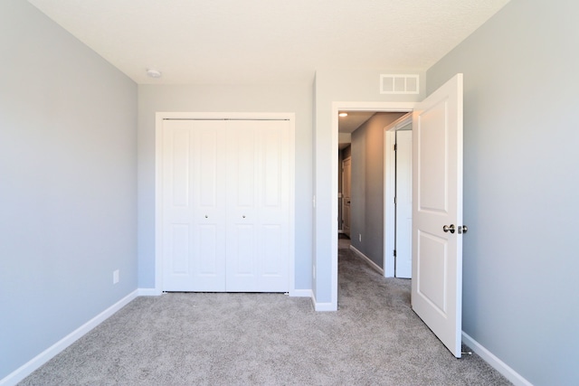 unfurnished bedroom with light colored carpet and a closet