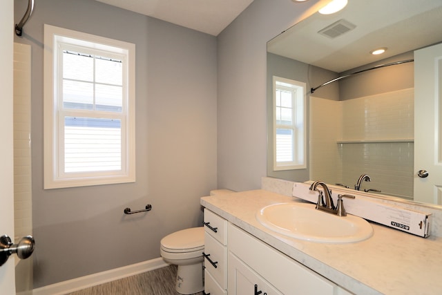 bathroom featuring vanity, toilet, walk in shower, and a healthy amount of sunlight