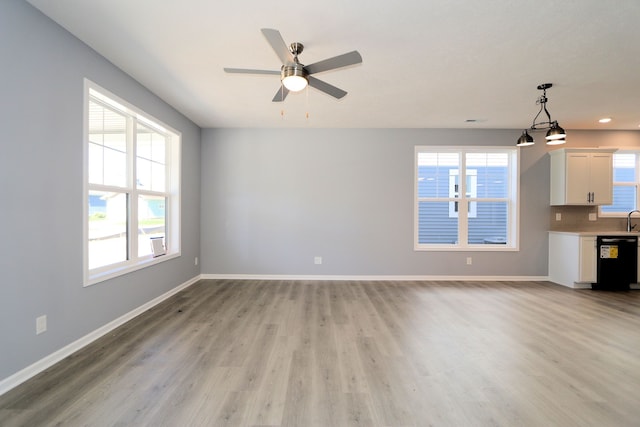 unfurnished living room with sink, light hardwood / wood-style flooring, a wealth of natural light, and ceiling fan