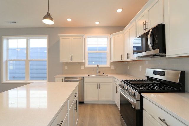 kitchen featuring sink, appliances with stainless steel finishes, decorative backsplash, white cabinets, and light wood-type flooring