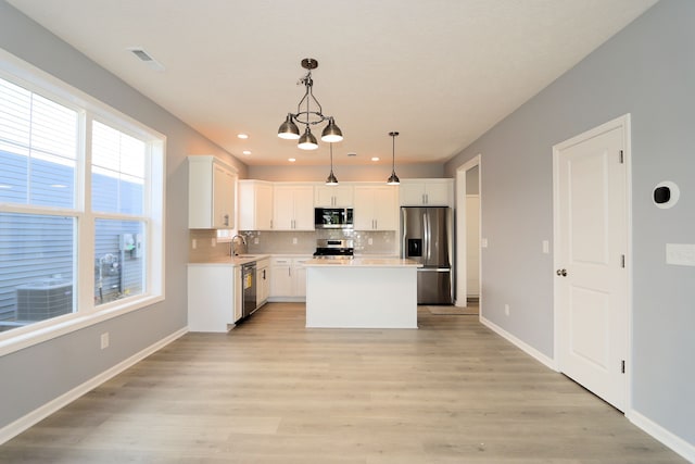 kitchen with white cabinetry, pendant lighting, a kitchen island, and stainless steel appliances