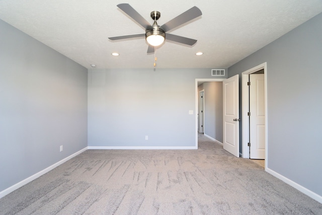 empty room with light carpet, a textured ceiling, and ceiling fan