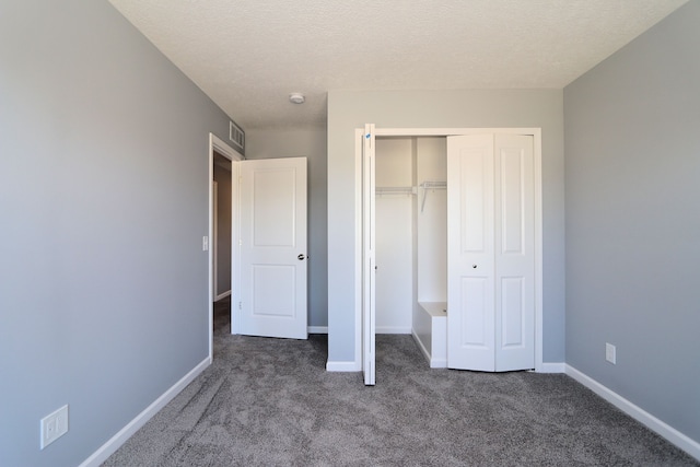 unfurnished bedroom featuring carpet, a textured ceiling, and a closet