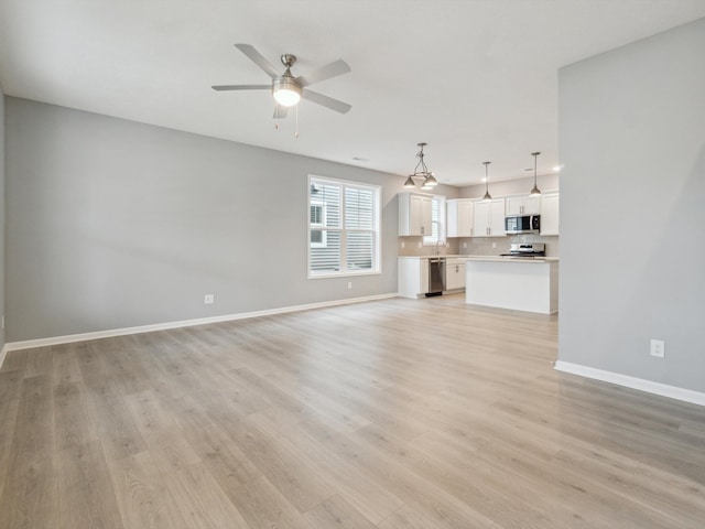 unfurnished living room featuring ceiling fan, sink, and light hardwood / wood-style floors