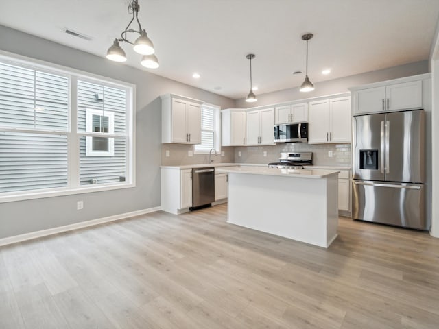 kitchen with white cabinetry, stainless steel appliances, and hanging light fixtures