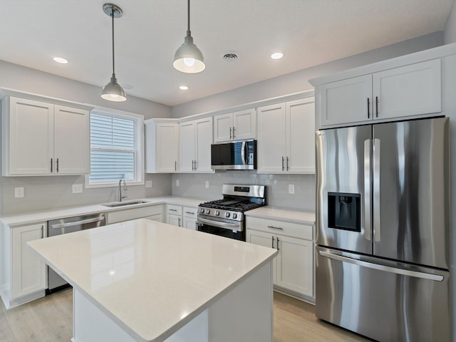 kitchen with appliances with stainless steel finishes, decorative light fixtures, white cabinetry, and sink