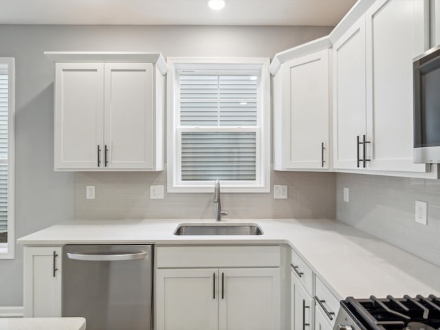 kitchen with dishwasher, sink, decorative backsplash, plenty of natural light, and white cabinetry