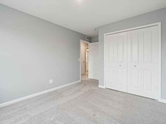 unfurnished bedroom featuring light carpet and a closet