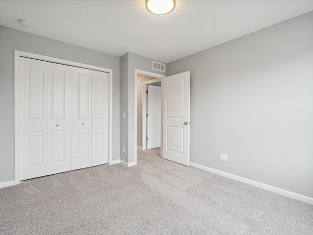 unfurnished bedroom with light colored carpet and a closet