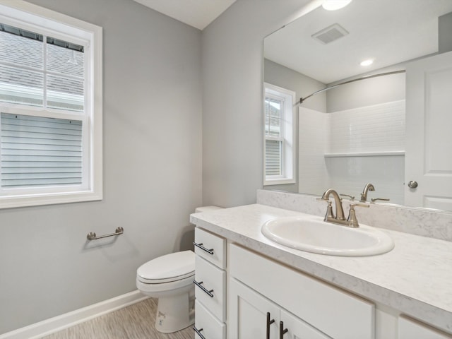 bathroom featuring walk in shower, vanity, and toilet