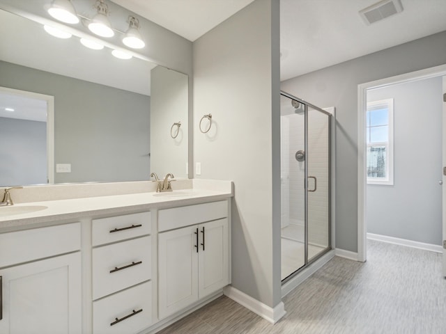 bathroom with wood-type flooring, vanity, and a shower with shower door