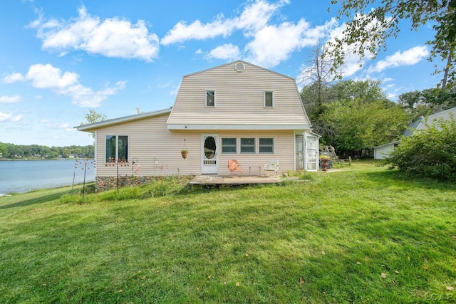 back of property with a water view and a lawn