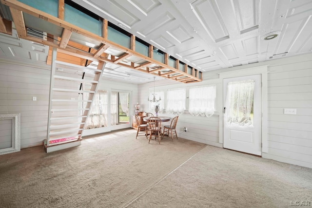 dining area with carpet flooring, an inviting chandelier, and wood walls