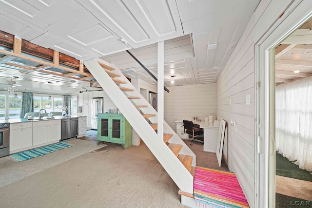 basement featuring carpet, sink, stainless steel refrigerator, and wood walls