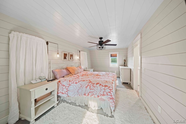 bedroom with ceiling fan and wooden walls