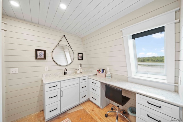 home office with light wood-type flooring, wood ceiling, wooden walls, and sink