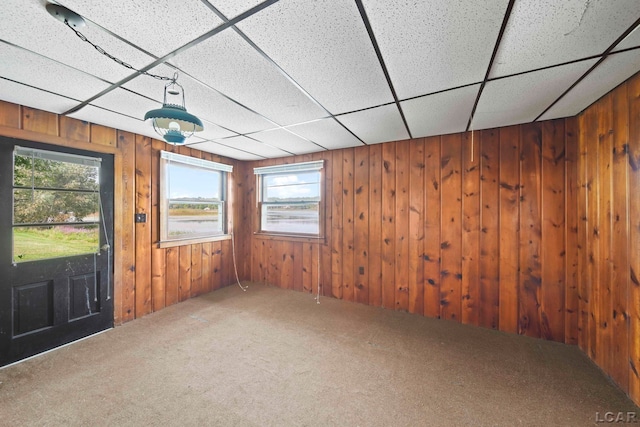 interior space featuring a paneled ceiling and wooden walls